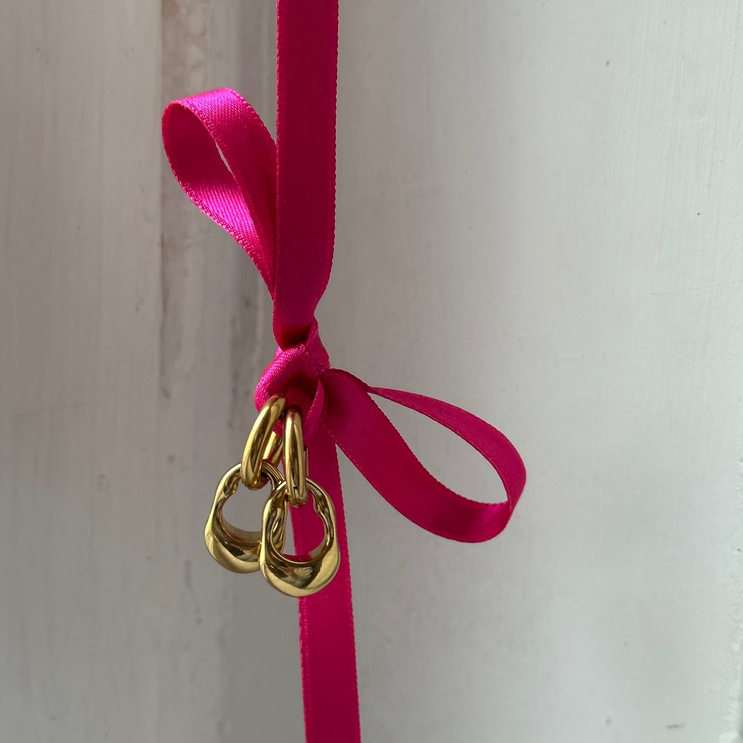 Ricky Hoops Ohrringe in Gold an einer Rosa Schleife