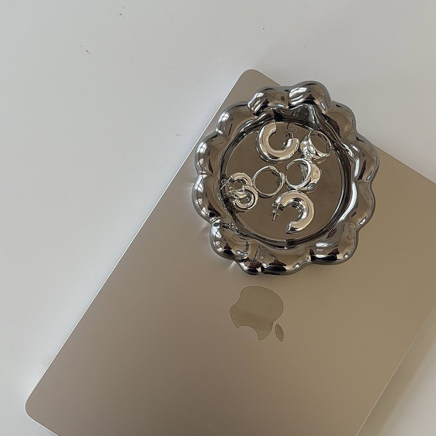 Kräftige Silberschmuckstücke in glänzendem Schmucktablett auf MacBook auf weißem Schreibtisch