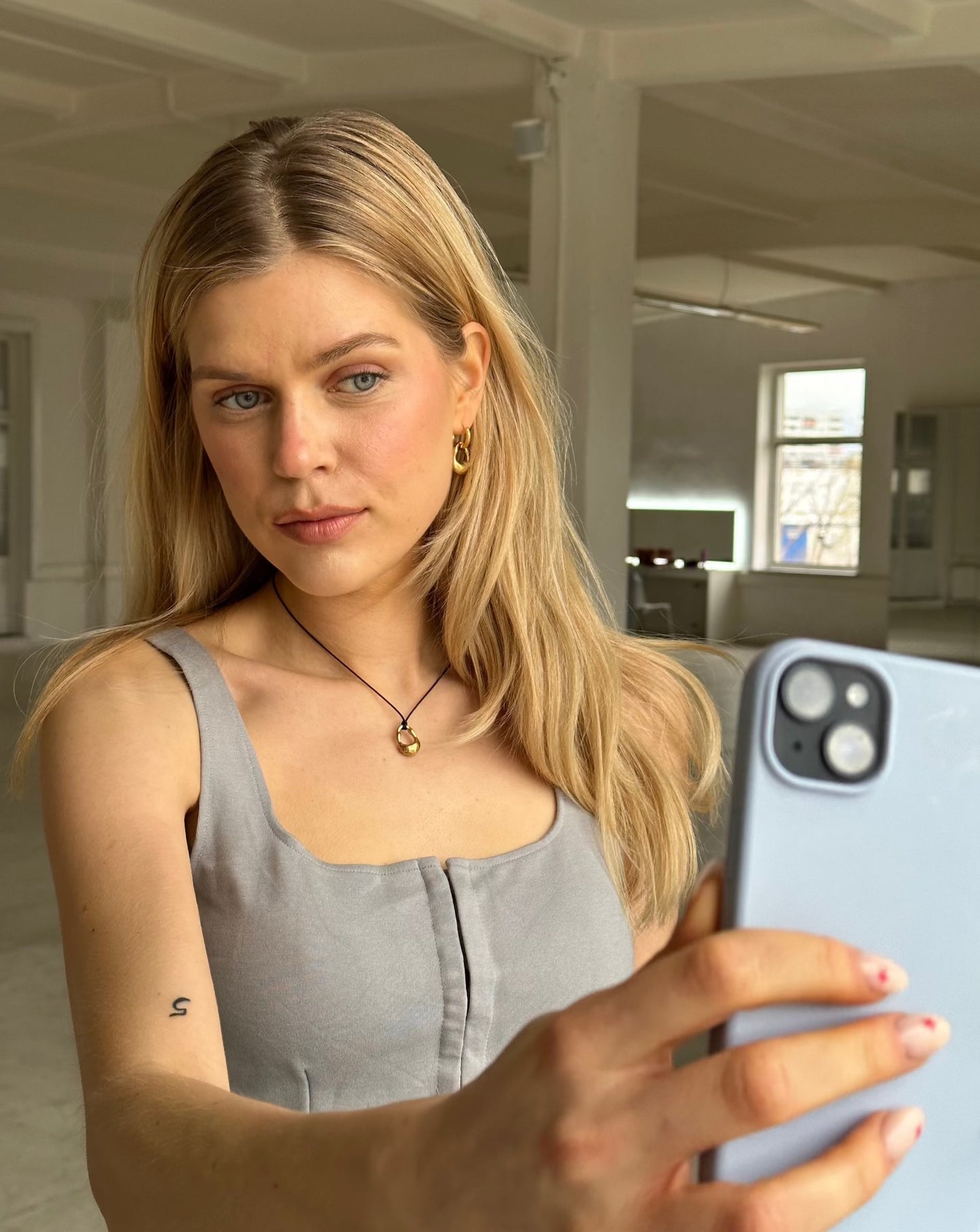 Ricky Halskette, getragen von einem blonden Mädchen mit Handy