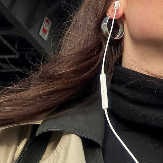 silver bella hoops worn on girl with headphones in on the streets close up