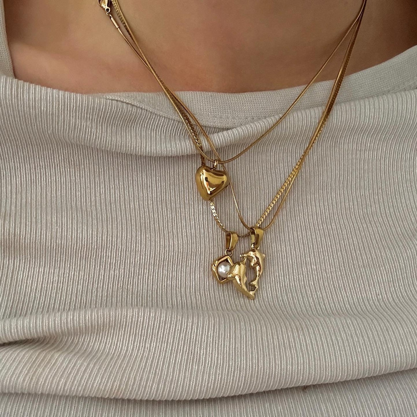 Dancing Dolphins Delfin Kette getragen mit Kani und Heart of Gold Kette auf beigem Oberteil