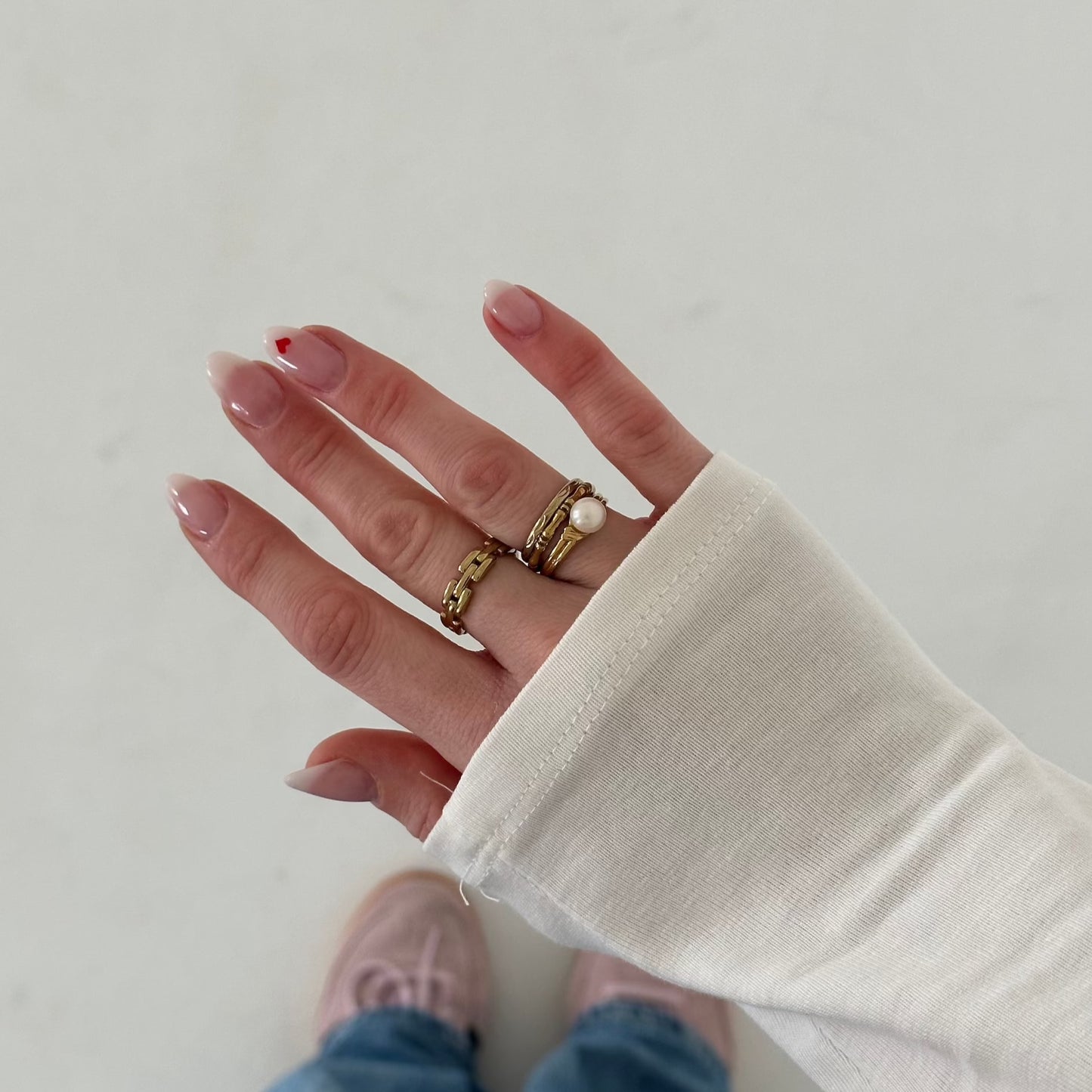 ring an einer Hand eines Mädchens mit weißem Shirt, vor weißer Wand