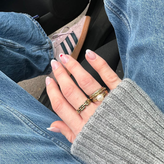 drei Ringe an der Hand von einem Mädchen mit Jeans