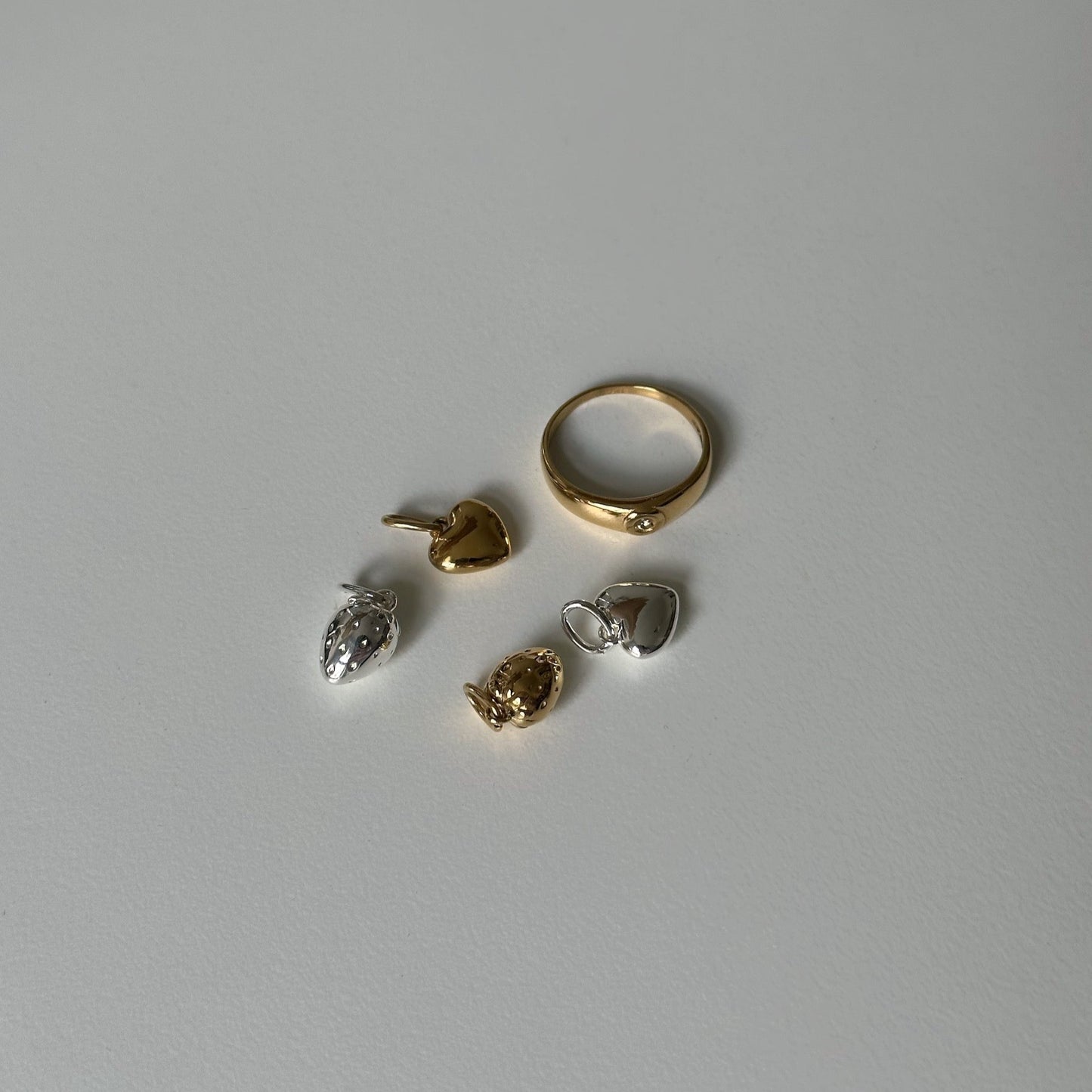 Gigi Ring und vier Charms auf weißem Tisch