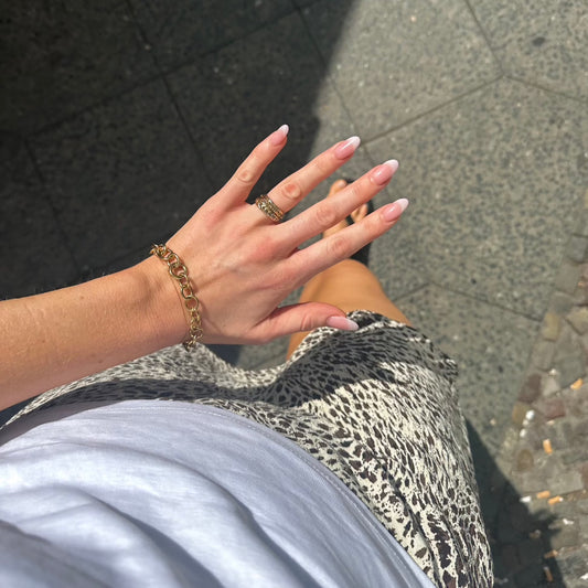 women walking on streets from above showing rings and oval link bracelet in gold