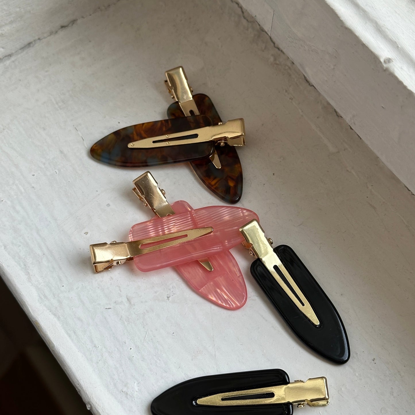 Skincare Clips in braun, rosa und schwarz auf weißer Fensterbank