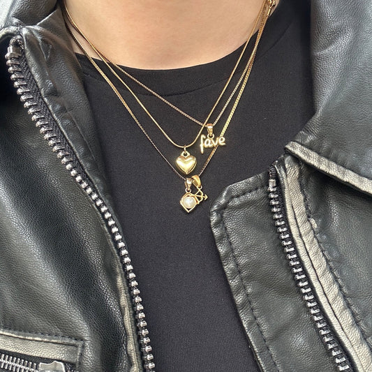 Three gold necklaces worn on black shirt 