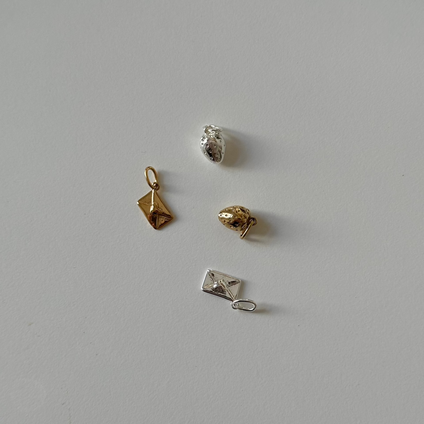 love letter and strawberry charm in silver and gold on white table 