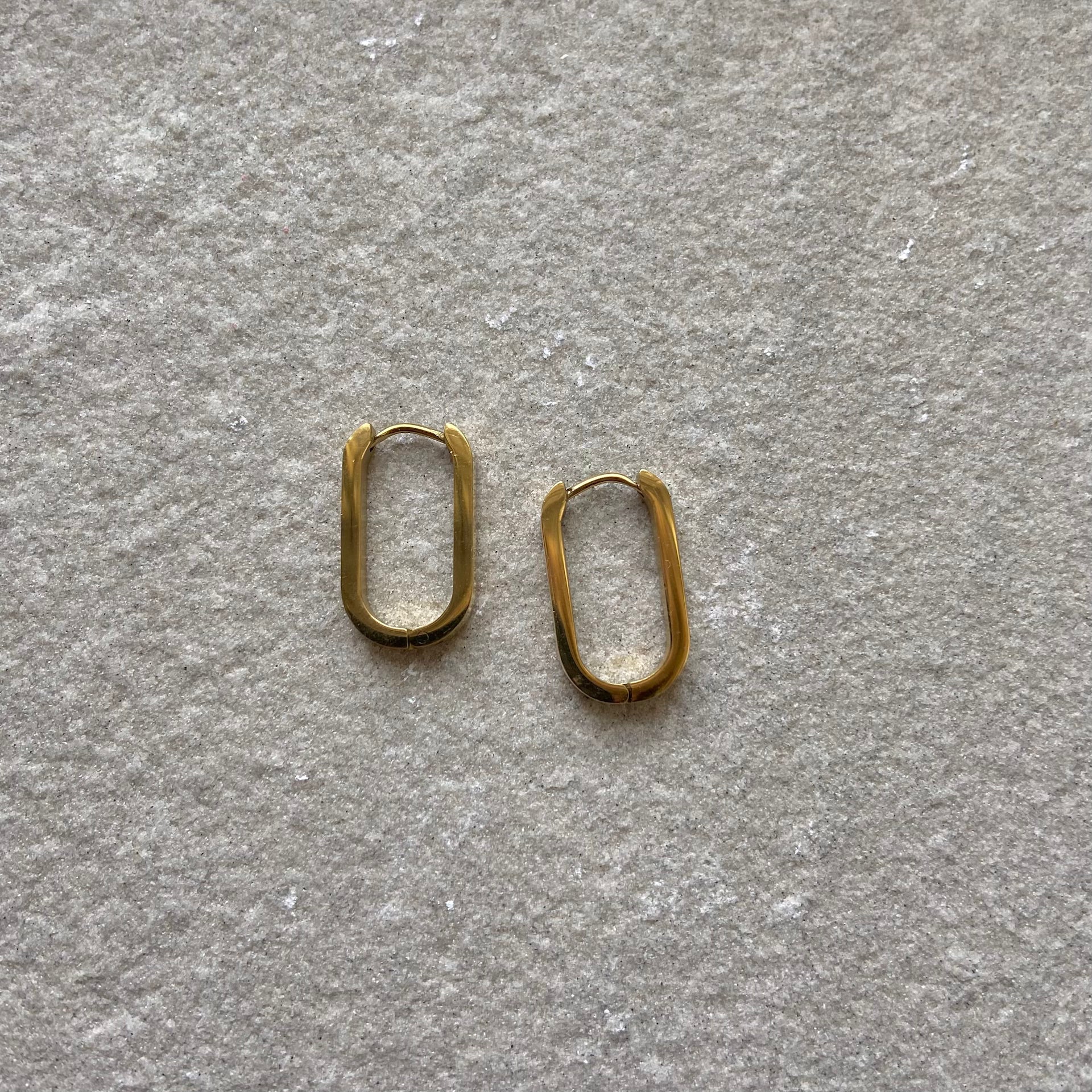 Oval Hoops Creolen Gold in gold auf weißer Steinplatte